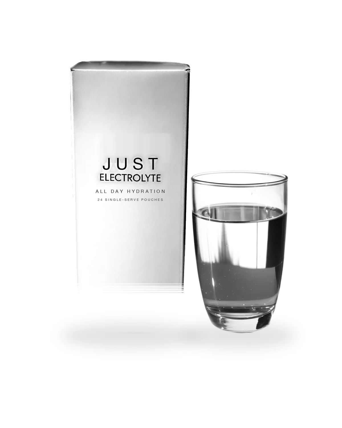 Just Electrolyte All Day Hydration white carton beside a clear glass of prepared electrolyte water, soft studio shadow on a white background