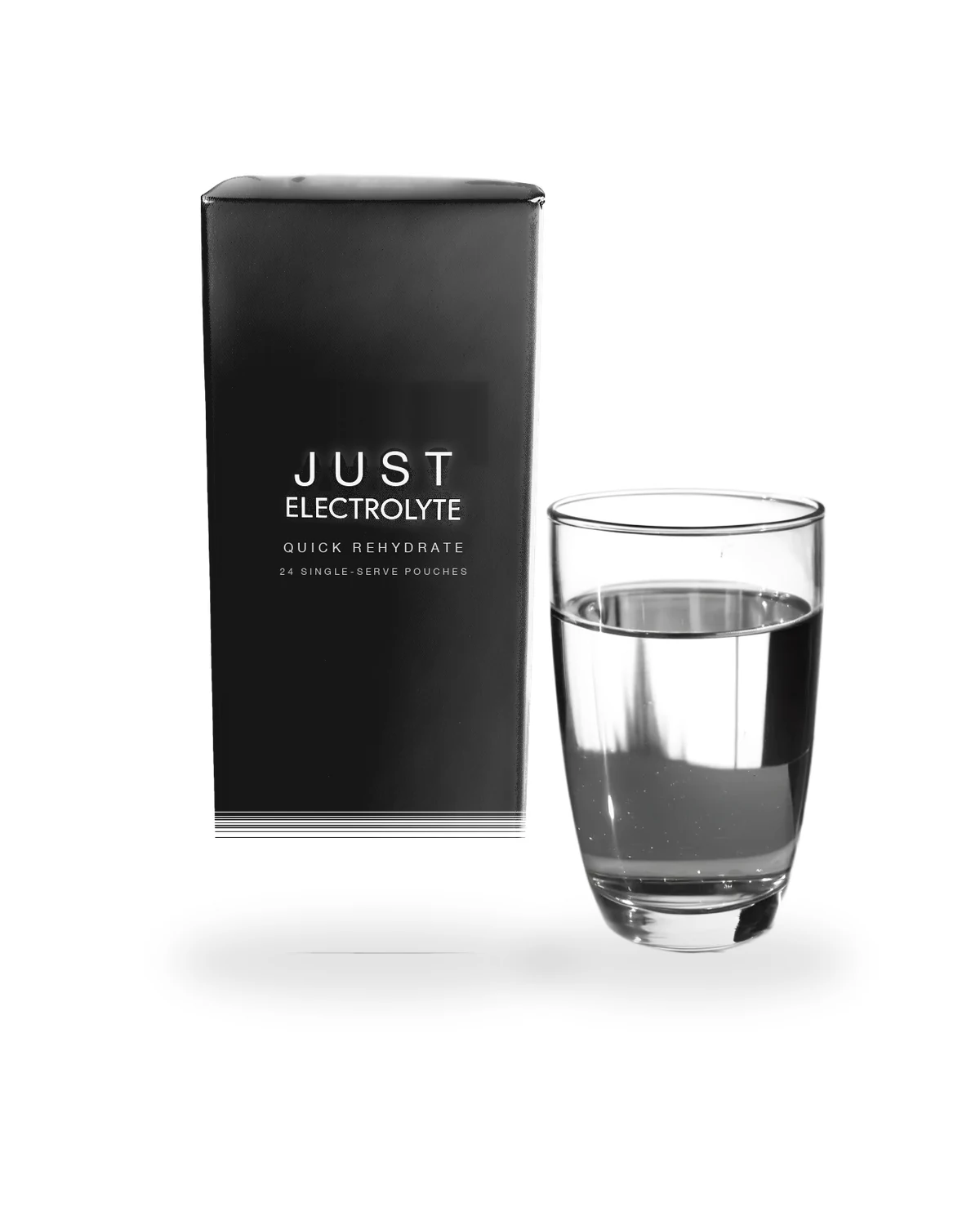 Just Electrolyte Quick Rehydrate matte-black carton beside a clear glass of prepared electrolyte water, soft studio shadow on a white background